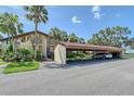 Exterior view of condo building with a car port and view of the property's mature landscaping at 6472 Seagull Dr # 301, Bradenton, FL 34210