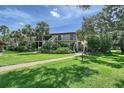 Exterior view of condo building with tropical landscaping, a sidewalk, and a second-story balcony at 6472 Seagull Dr # 301, Bradenton, FL 34210