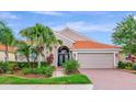 Charming single-story home featuring a red tile roof, brick driveway, and lush tropical landscaping at 6845 74Th Street E Cir, Bradenton, FL 34203