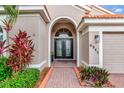 Close-up of an entryway showcasing double doors with decorative glass and surrounding tropical landscaping at 6845 74Th Street E Cir, Bradenton, FL 34203