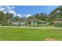 Landscaped home featuring a vibrant green lawn and mature trees under a blue sky at 7604 Weeping Willow Cir, Sarasota, FL 34241