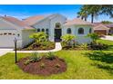Beautiful front yard with walkway leading to home, lush garden beds, and palm trees at 7727 Heyward Cir, University Park, FL 34201