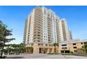 View of the building's exterior featuring its grand architecture, lush landscaping, and convenient guest parking area at 800 N Tamiami Trl # 405, Sarasota, FL 34236