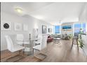 Well-lit living and dining area with wood floors, modern furnishings, and stunning water view from the large windows at 800 N Tamiami Trl # 405, Sarasota, FL 34236