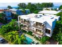 Aerial view of a modern white building with balconies and a refreshing pool surrounded by tropical foliage at 804 N Shore Dr, Anna Maria, FL 34216