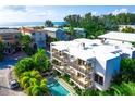 Aerial view of a modern white building with balconies, a refreshing pool, and lush tropical surroundings at 804 N Shore Dr, Anna Maria, FL 34216