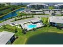 Aerial view of community pool and amenity center surrounded by lush landscaping and parking at 850 Tidewater Shores Loop # 102, Bradenton, FL 34208