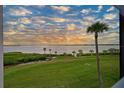 Exterior view featuring green lawn, tropical palm trees, and a stunning view of the water and colorful sky at 850 Tidewater Shores Loop # 102, Bradenton, FL 34208