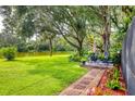 Serene backyard with lush lawn, mature trees, seating area, and a tranquil lake view at 8717 Misty Creek Dr, Sarasota, FL 34241