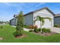 Charming single-story home with lush landscaping, including palm trees and flowering shrubs, leading to the garage at 9566 Coastline Way, Parrish, FL 34219