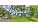 Expansive light blue home with a manicured lawn and mature trees at 1076 Toc0Baga, Sarasota, FL 34234
