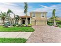 Attractive two-story home boasts a brick driveway, manicured lawn, and tropical landscaping at 12814 Daisy Pl, Bradenton, FL 34212