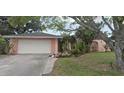 Charming single-story home showcasing a well-maintained front yard, attached two-car garage, and pink exterior paint at 1308 63Rd Nw St, Bradenton, FL 34209