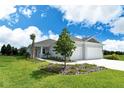 Well-maintained home featuring a manicured lawn, decorative trees, and a spacious two-car garage at 13908 Painted Loop, Parrish, FL 34219