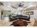 Expansive living room featuring travertine floors, tray ceilings, a large leather sectional, and an open concept layout at 15780 Wilson Rd, Sarasota, FL 34240