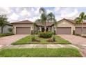 Charming home with a paved driveway, two-car garage, and lush landscaping at 17648 Northwood Pl, Lakewood Ranch, FL 34202