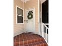 Inviting front door with a wreath, complemented by stylish tiled steps and neutral siding at 1801 Highland Rd, Osprey, FL 34229