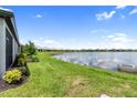 Serene backyard view of a lake with lush green grass and neighboring houses in the distance at 18039 Cherished Loop, Bradenton, FL 34211