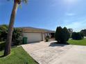 View of the home's exterior, showcasing the two-car garage and manicured landscaping against a clear blue sky at 19358 Edgewater Dr, Port Charlotte, FL 33948