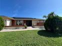 Inviting single-story home showcasing solar panels and a lush, green lawn under a bright, clear blue sky at 19358 Edgewater Dr, Port Charlotte, FL 33948