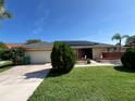 Charming single-story home featuring solar panels, a two-car garage, and a well-manicured lawn under a clear blue sky at 19358 Edgewater Dr, Port Charlotte, FL 33948