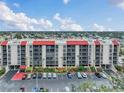Wide exterior shot of a condominium building with a red roof and parking lot on a sunny day at 21405 Olean Blvd # 224, Port Charlotte, FL 33952