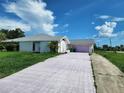 Exterior shot of the driveway and home, with a gray roof and bright blue sky at 4354 Rock Creek Dr, Port Charlotte, FL 33948