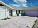 Close exterior shot of the driveway and garage, featuring garbage cans and a gray roof at 4354 Rock Creek Dr, Port Charlotte, FL 33948