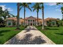 Beautifully landscaped home with manicured lawn, brick driveway, palm trees, and symmetrical design creates curb appeal at 550 Dove Pointe, Osprey, FL 34229