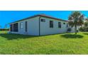 Back of home featuring a screened-in patio and lush green lawn at 8045 Bosco Rd, Port Charlotte, FL 33981