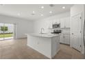 Bright kitchen featuring stainless steel appliances, tile flooring and a center island with a sink at 8705 Winter Breeze Way, Sarasota, FL 34241