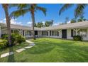 Beautiful house featuring white facade, dark shutters, and a lush green lawn with tropical palm trees for a relaxing view at 1408 99Th Nw St, Bradenton, FL 34209