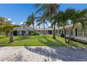 Expansive front yard featuring a meticulously maintained lawn and a charming white home framed by swaying palm trees at 1408 99Th Nw St, Bradenton, FL 34209
