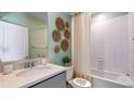 Cozy bathroom with white tiled shower, decorative wall art, and a modern vanity with a sleek countertop at 18329 Thistleberry Pl, Lakewood Ranch, FL 34211