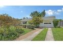 Home featuring a long driveway, garage, and landscaped front yard with mature trees at 2088 Grove St, Sarasota, FL 34239