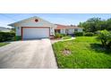 Well-maintained home featuring an attached garage, mature landscaping, and a concrete driveway at 22378 Peachland Blvd, Port Charlotte, FL 33954