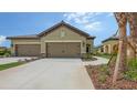 Beige two-car garage with paved driveway and stone accents in a Florida community at 248 Altamura Cir, Nokomis, FL 34275