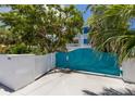 Exterior shot showcasing the driveway, unique blue gate, and lush landscaping at 401 N Bay Blvd, Anna Maria, FL 34216