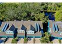 Aerial view showcasing the blue townhomes, dark roofs, and surrounding trees and pond at 4532 Chinkapin Dr, Sarasota, FL 34232