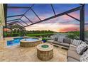 Gorgeous backyard featuring a pool, jacuzzi, outdoor seating, and a serene view of the lake at sunset at 4915 Kiva Cir, Bradenton, FL 34211