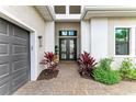 Inviting front entrance featuring a brick pathway, double doors, a two car garage, and colorful landscaping at 4915 Kiva Cir, Bradenton, FL 34211