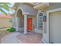 Covered front entrance featuring brickwork, columns, transom windows, and an orange front door at 695 Rivendell Blvd, Osprey, FL 34229