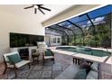 Outdoor living area with a screened pool and spa, grill area, ceiling fan and comfortable seating at 7211 Marston Ct, University Park, FL 34201