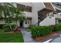 Exterior view of condo with well-manicured landscape, stairs leading to unit, and palm tree. Number 7301 is visible at 7301 W. Country Club N Dr # 108, Sarasota, FL 34243