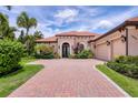 Beautiful home features a tile roof, pristine landscaping, and a brick driveway for added curb appeal at 7605 Haddington Cv, Lakewood Ranch, FL 34202