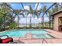 Screened-in pool and spa overlook a serene lake view, creating a relaxing outdoor oasis at 7605 Haddington Cv, Lakewood Ranch, FL 34202