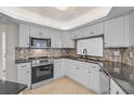 Bright kitchen boasts stainless steel appliances, tile flooring, white cabinets, and a decorative backsplash at 1674 Cottonwood Trl, Sarasota, FL 34232