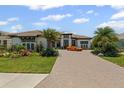 Beautiful home with lush landscaping, a stone paver driveway, and an orange sports car at 3936 Santa Caterina Blvd, Bradenton, FL 34211