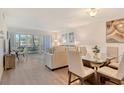 Bright living room with dining area, patio doors to screened lanai, light walls and wood floors at 4380 Exeter Dr # 204, Longboat Key, FL 34228