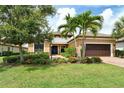 Beautiful single Gathering home featuring a tile roof, brick driveway, and lush landscaping with palm trees at 4916 Tivoli Run, Bradenton, FL 34211